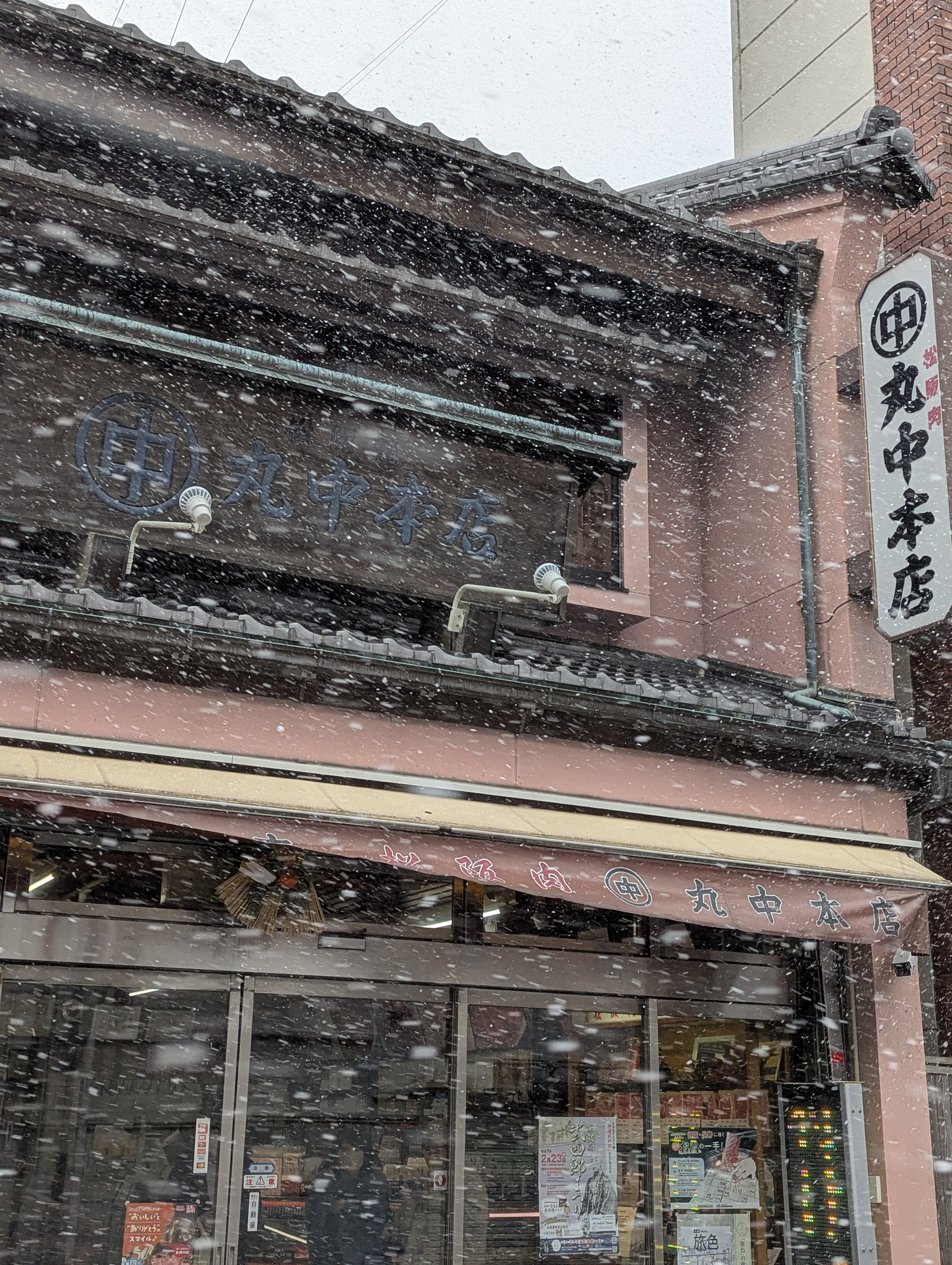 舞う雪と丸中本店外観